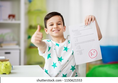 childhood, education and people concept - happy smiling boy holding school test with a grade showing thumbs up - Shutterstock ID 1150621553
