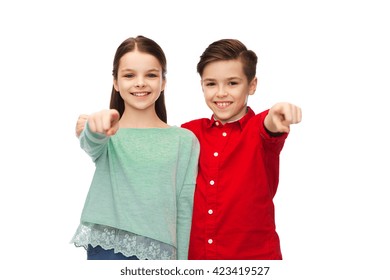 Childhood, Fashion, Gesture And People Concept - Happy Smiling Boy And Girl Hugging And Pointing Finger To You