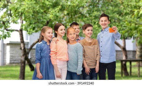 Childhood, Friendship, Technology And People Concept - Happy Children Talking Selfie By Smartphone Over Private House Backyard Background