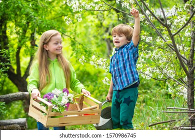 Childhood And Growing Up. Children Play In Spring Garden. Little Cute Boy Rise His Hand And Girl Looking At Him. Young Generation Of Tree Huggers And Nature Lovers. Childchood And Outdoor Leisure