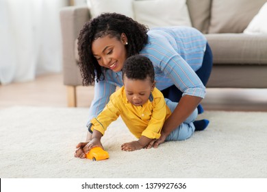 Childhood, Kids And People Concept - Happy African American Mother And Her Baby Son Playing With Toy Car Together On Sofa At Home