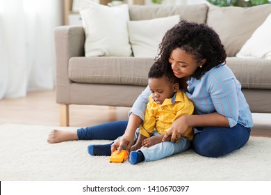 Childhood, Kids And People Concept - Happy African American Mother And Her Baby Son Playing With Toy Car Together On Sofa At Home