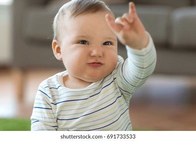 childhood, kids and people concept - lovely baby boy showing rock hand sign at home