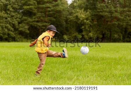 childhood, leisure games and people concept - happy little boy with ball playing soccer at summer park