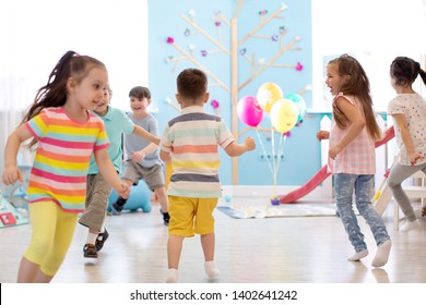 Childhood, Leisure And People Concept - Group Of Happy Children Playing Tag Game And Running Indoors