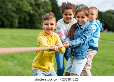 childhood, leisure and people concept - group of happy kids playing tug-of-war game and running at park