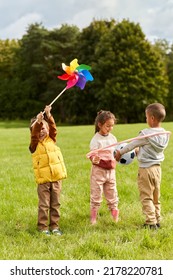 Childhood, Leisure And People Concept - Happy Kids With Pinwheel Having Fun At Park