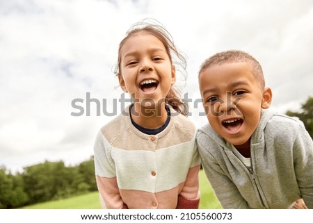 childhood, leisure and people concept - happy smiling little boy and girl at park