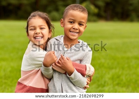 childhood, leisure and people concept - happy smiling little boy and girl hugging at park