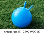 childhood, leisure and toys concept - close up of red bouncing ball or hoppers on grass