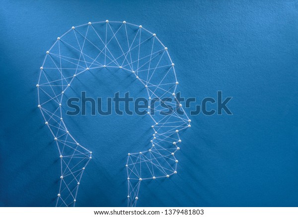Childhood nostalgia concept. Network of pins and threads in the shape of a cut out child head inside a man head symbolising the inner child inside every human beign.  