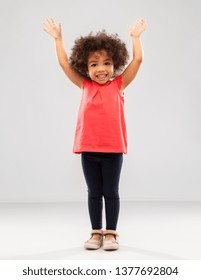 Childhood And People Concept - Happy Little African American Girl With Hands Up Over Grey Background