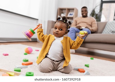 childhood and people concept - little african american baby girl playing with toy blocks at home