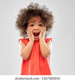 childhood and people concept - surprised or scared little african american girl screaming over grey background