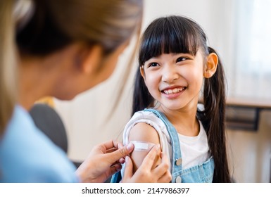 Childhood Vaccination. Asian Young Woman Doctor Vaccinating Little Girl At Home. Vaccine For Covid-19 Coronavirus, Flu, Infectious Diseases.