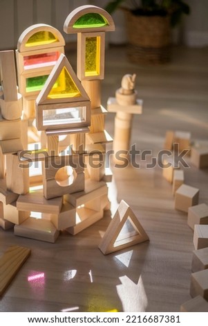 Childish castle with towers wooden colored glass Montessori materials at sunny shine shadow at room. Kids early imagination intelligence development building construction bricks details plaything toys