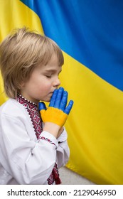 Children against war. Russia's invasion of Ukraine, request for world community's help. A child against background of Ukrainian flag with hands painted in yellow and blue, gesture of faith and hope