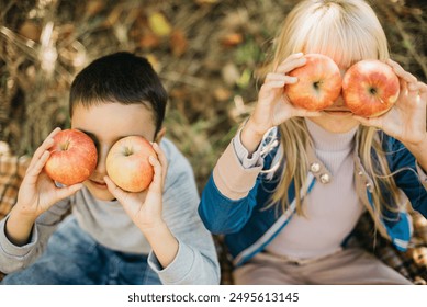 Children with Apple in Orchard. Harvest Concept. Garden, boy and blonde girl eating fruits at fall. Child picking apples on farm in autumn. Healthy nutrition Garden Food. - Powered by Shutterstock