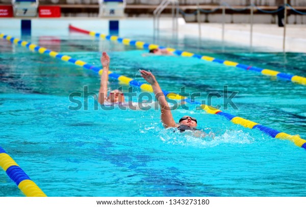 Children backstroke swimming\
training in swimming pool. The goal of competitive swimming is to\
improve speed, and to beat other competitors in\
events
