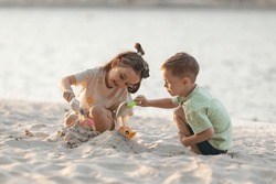 Children Boy And Girl Playing On The Beach On Summer Holidays. Children Having Fun With A Sand On The Seashore. Vacation Concept. Happy Sunny Day