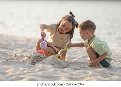 Children boy and girl playing on the beach on summer holidays. Children having fun with a sand on the seashore. Vacation concept. Happy sunny day - Powered by Shutterstock