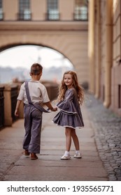 Children boy and girl in retro clothes are walking down the street holding hands. The little girl turned around. Romantic, historical image. Selective focus 