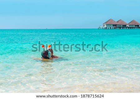 children a boy and a girl swim near the shore in a full face snorkeling mask in Maldives