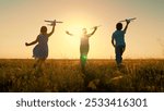 Children boy play with toy airplane outdoor, Silhouette. Future pilot. Child pilot runs with toy plane across field against sky. Child wants to become an astronaut. Play, Kids girl boy dreams of fly