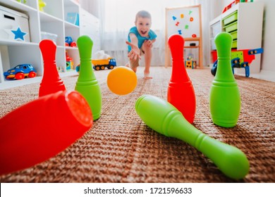 children a boy throws ball into a home bowling alley and smashes the bowling pins. Selective focus. concept of active play in the home room, quarantine, self-isolation, achieving goal