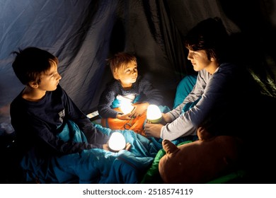 Children, boys siblings, enjoying a night in a tent in camping, laughing and reading books - Powered by Shutterstock