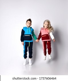 Children, brother and sister, in colorful tracksuits and sneakers. They holding hands, jumping up, isolated on white background. Childhood, fashion, advertising and sport. Full length, copy space - Shutterstock ID 1737606464