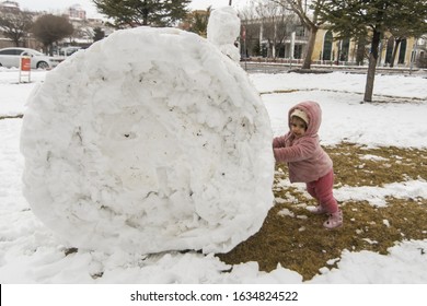 Children Build Snowman. Kids Building Snow Man Playing Outdoors On Sunny Snowy Winter Day. Boy And Girl Play Snow Balls. Winter Clothing For Baby And Toddler.