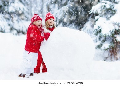 Children Build Snowman. Kids Building Snow Man Playing Outdoors On Sunny Snowy Winter Day. Outdoor Family Fun On Christmas Vacation. Boy And Girl Play Snow Balls. Winter Clothing For Baby And Toddler.