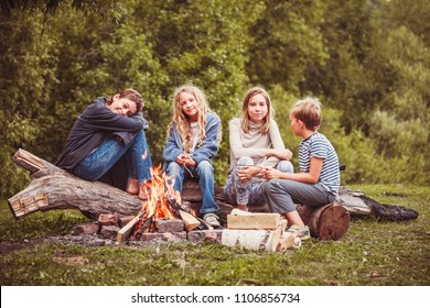 Children in the camp by the fire. Group teen outdoors at summer