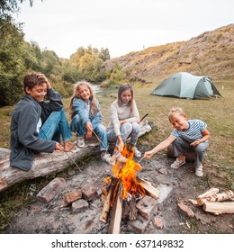 Children In The Camp By The Fire. Group Teen Outdoors At Summer