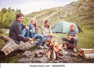 Children In The Camp By The Fire. Group Teen Outdoors At Summer