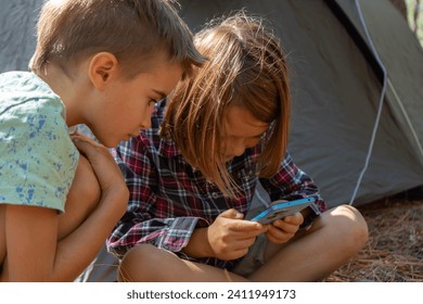 Children camping in the forest playing with smartphone - Powered by Shutterstock