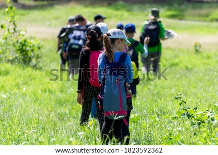 Children and care teachers Was walking through a wide meadow In school field day activities.