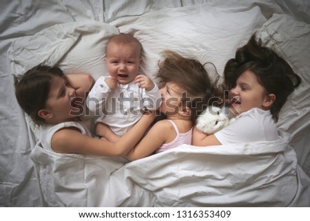 Similar – Image, Stock Photo Happy little girl holding doll and cookie while woman playing with a boy over the bed. Weekend family leisure time concept.