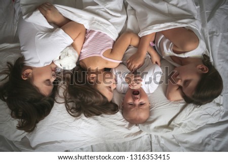 Similar – Image, Stock Photo Happy little girl holding doll and cookie while woman playing with a boy over the bed. Weekend family leisure time concept.