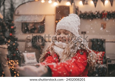 Children celebrating Christmas and New Year winter holidays season outdoor waiting Santa. Kids joyful spending time together near Xmas camper trailer rejoices at first snow enjoying childhood