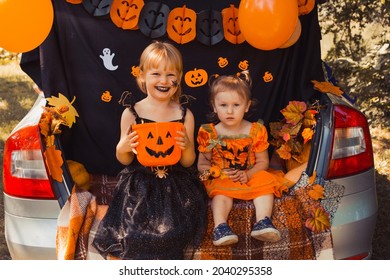 Children celebrating Halloween in trunk of car.