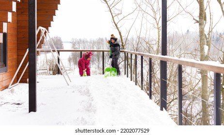 Children Clean The Terrace Of Their House With Shovels. Little Helpers Shovel Snow. Family Activities In Winter Outdoors. Involving Children In Housework Concept. Kids Shoveling Snow On Sunny Day.