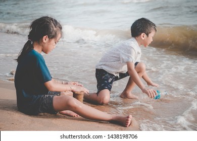 Children Is Cleaning Up Garbage On The Beach For Enviromental Clean Up Concept