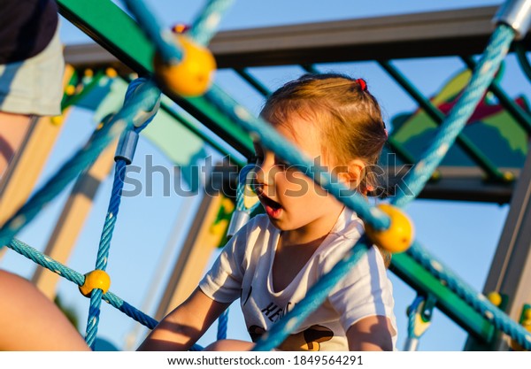 children climb on all fours on the rope bridge\
in the playground