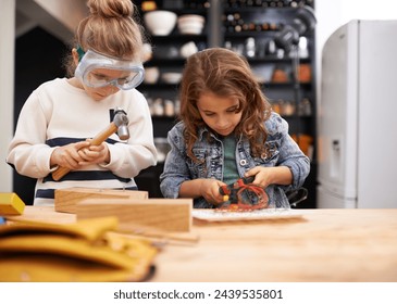 Children, construction and building in workshop with tools, play and game in kitchen of home. Girls, hammer and safety glasses for wood project on weekend, carpentry and woodworking or manufacture - Powered by Shutterstock