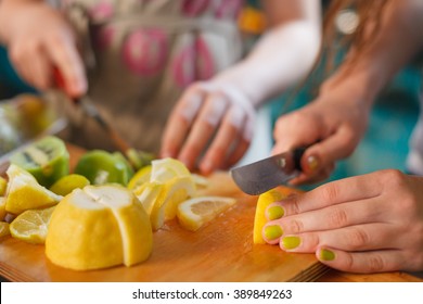 Children Cooking At The Kitchen. Hands Cutting Fresh Organic Lemons On The Wooden Table. Fruit Snack. Kids Making Lemonade.