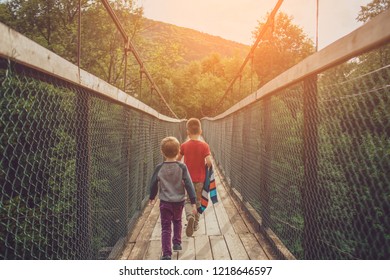 Children Crossing A Rope Bridge Across The River 