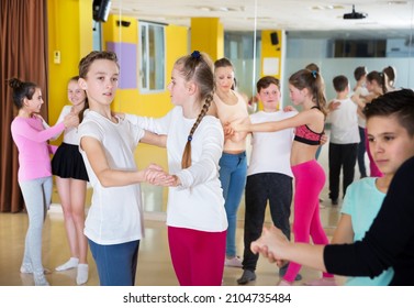 Children dancing together slow ballroom dances in pairs in the choreography class with female trainer