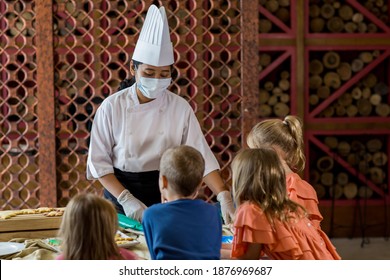 Children Decorating Christmas Biscuits And Gingerbread Cookies In Kitchen Together With Chef. Kids Cooking Class. Merry Christmas And Happy Holidays Concept